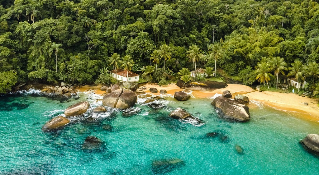 Luxurious oceanfront hotel with infinity pool overlooking emerald waters, private beach and mountains in Angra dos Reis, Brazil