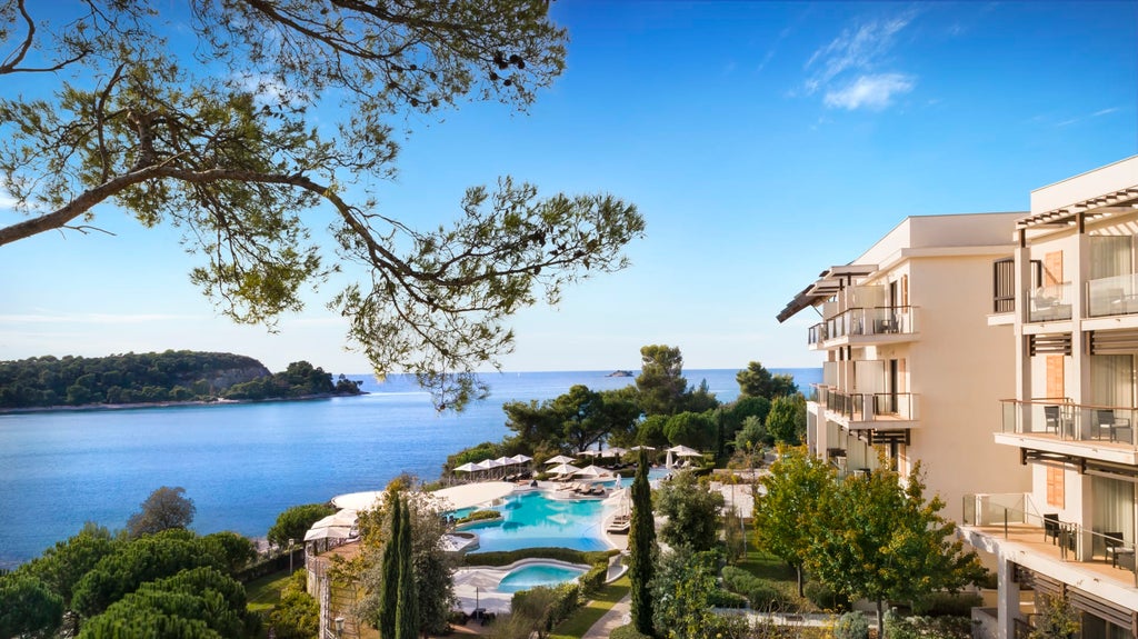 Luxurious seaside Monte Mulini Hotel with modern architecture nestled among pine trees, overlooking pristine Adriatic waters in Rovinj