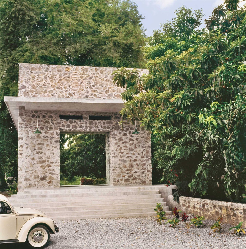 Elegant colonial-style Mexican hotel with lush tropical gardens, white-washed walls, vibrant bougainvillea, and terracotta tile accents near scenic coastline