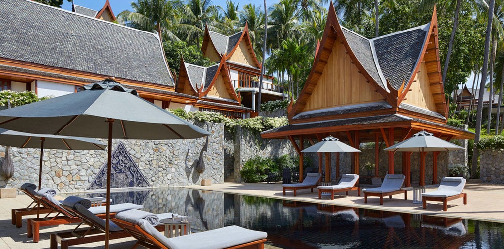 Modern villa bedroom featuring a king-size bed with crisp linens, wood-paneled walls, floor-to-ceiling windows and contemporary Thai decor