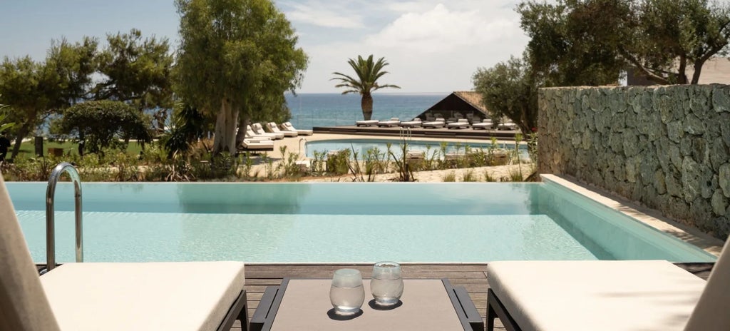 Elegant patio junior suite with white minimalist design, sea view, private balcony overlooking azure Corfu waters and lush Mediterranean landscape