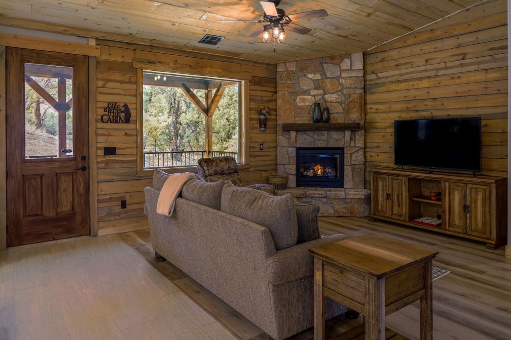 Rustic wooden lodge room with large windows overlooking scenic mountain landscape, plush bedding, and elegant southwestern-inspired interior design at mountain retreat