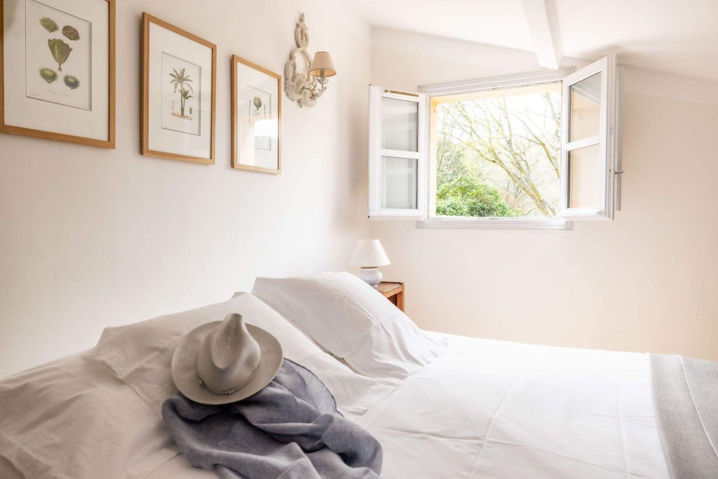 Elegant French countryside hotel room with soft neutral tones, antique wooden furniture, and delicate floral accents, showcasing refined Provençal style