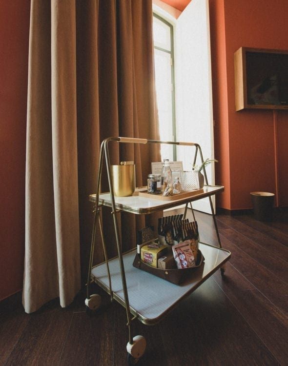 Elegant vintage-style hotel room with plush white bedding, classic wooden furniture, and soft ambient lighting in a luxurious Portuguese boutique hotel