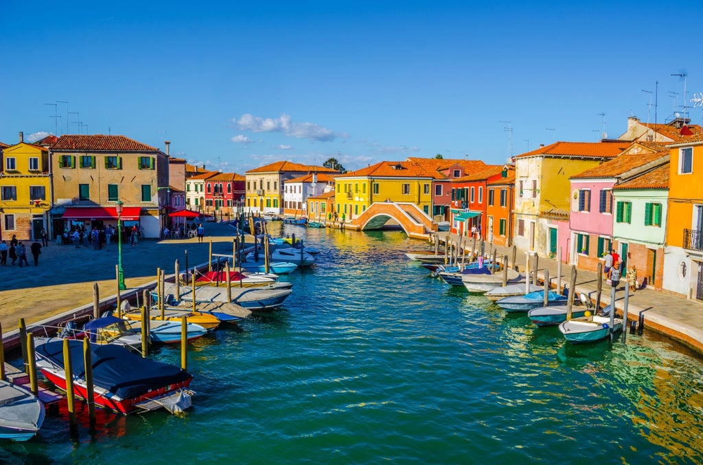 Traditional Italian water taxi crossing Venice lagoon with views of colorful Burano houses and artisan glass shops along canals