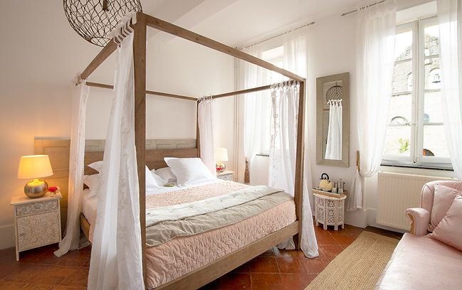 Elegant French hotel room with crisp white linens, minimalist design, large windows, and soft natural light creating a serene, luxurious ambiance.