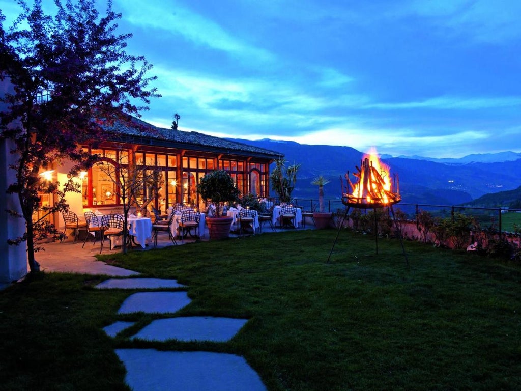 Medieval stone tower hotel nestled in Italian Dolomites with panoramic mountain views, featuring rustic luxury architecture and balconies