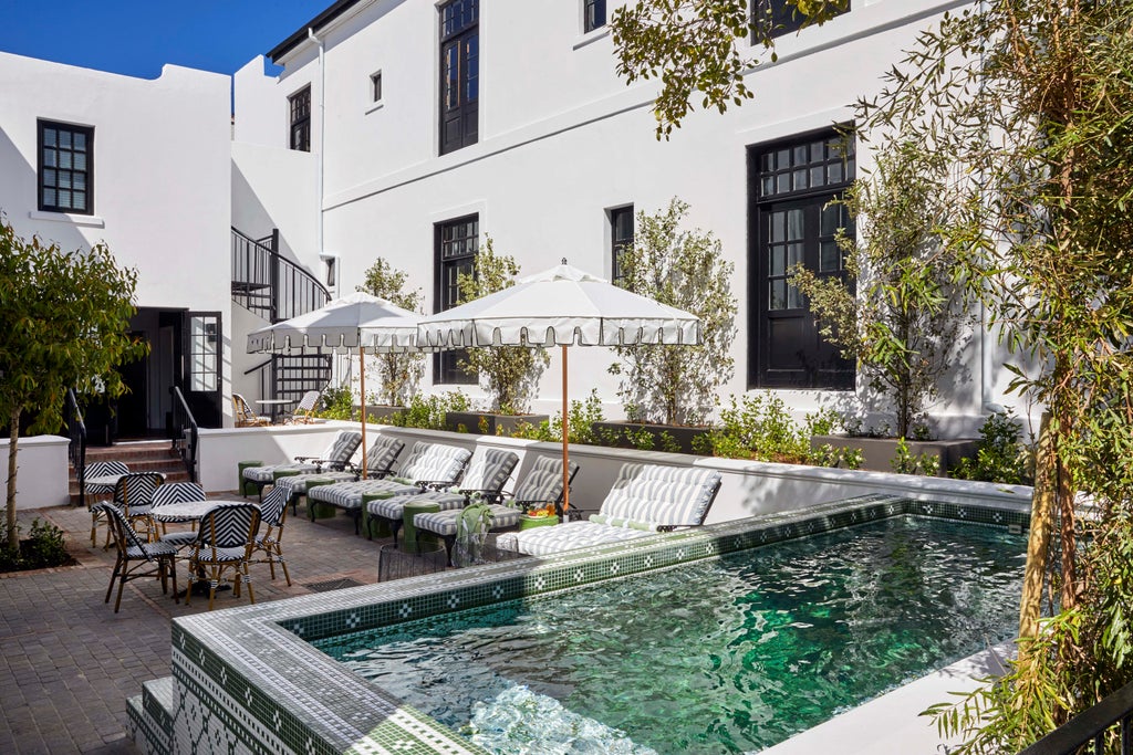 Historic luxury hotel in Cape Town with white Georgian-style facade, balconies with wrought-iron railings, and manicured gardens