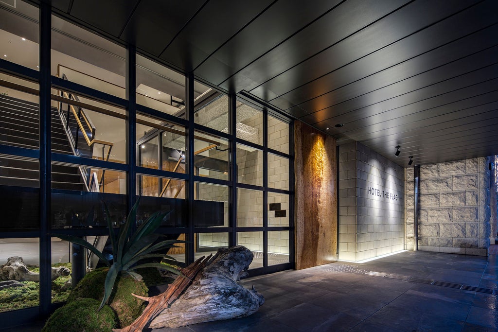 Modern luxury hotel exterior with geometric glass facade, illuminated entrance and 