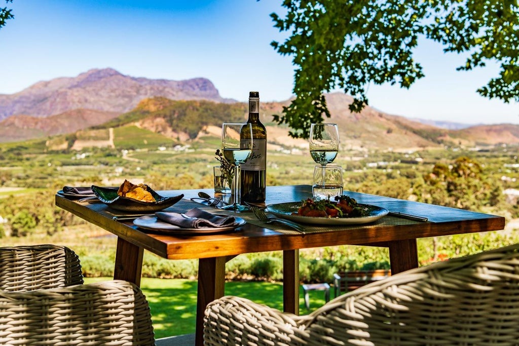 Elegant boutique hotel nestled in South African wine country with panoramic mountain views, stone walls and manicured gardens