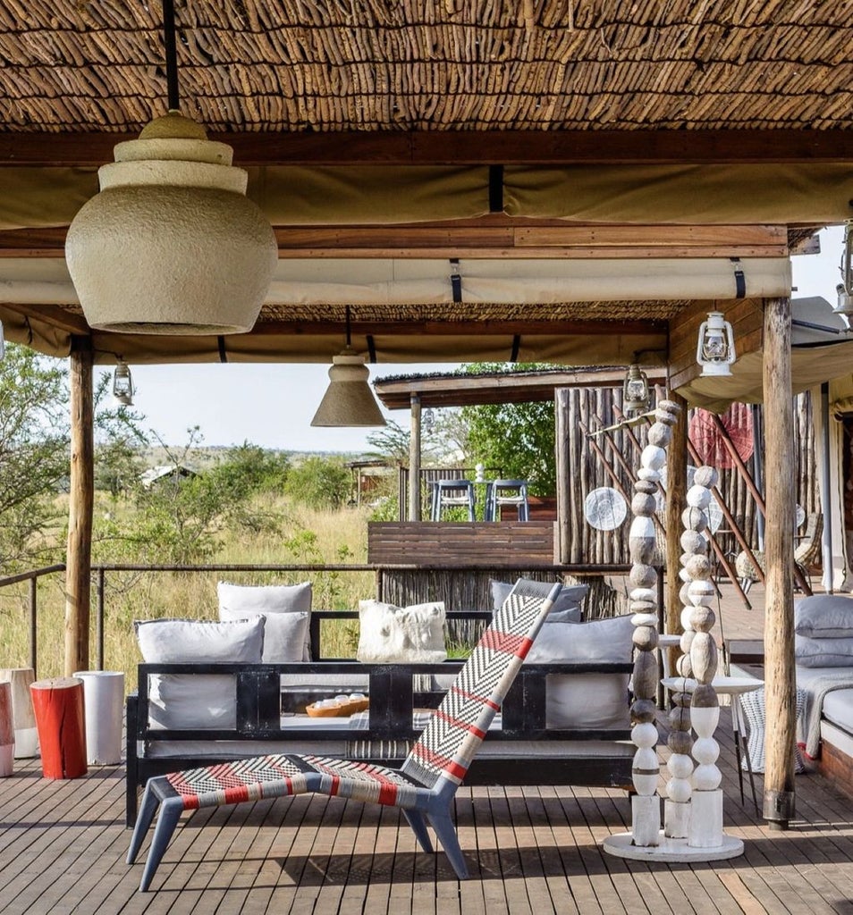 Luxurious safari tent overlooking Mara River at sunset, featuring modern canvas suite with private viewing deck and natural decor