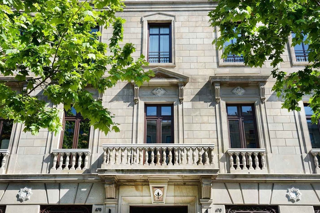 White marble hotel exterior with arched windows, elegant balconies and a palm-lined entrance featuring classic Mediterranean architecture