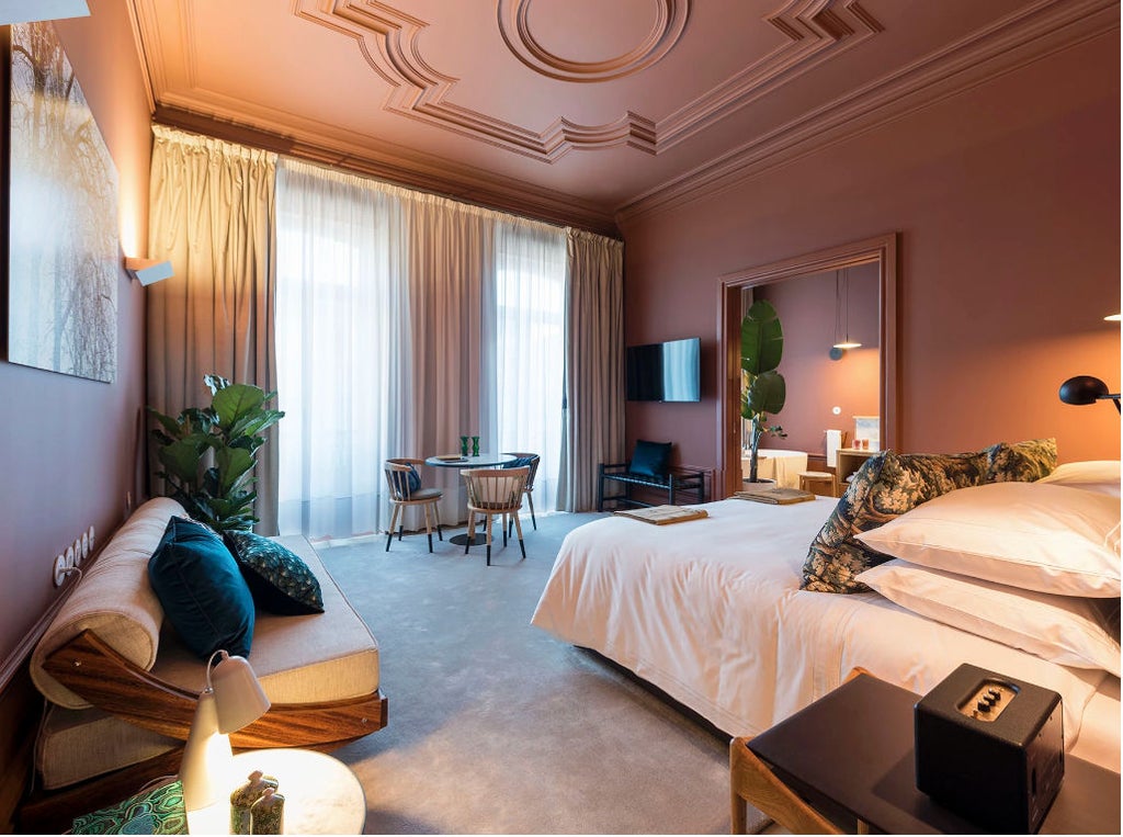 Elegant suite with white-draped canopy bed, exposed stone walls, crystal chandelier, and ornate full-length mirror in Porto guesthouse