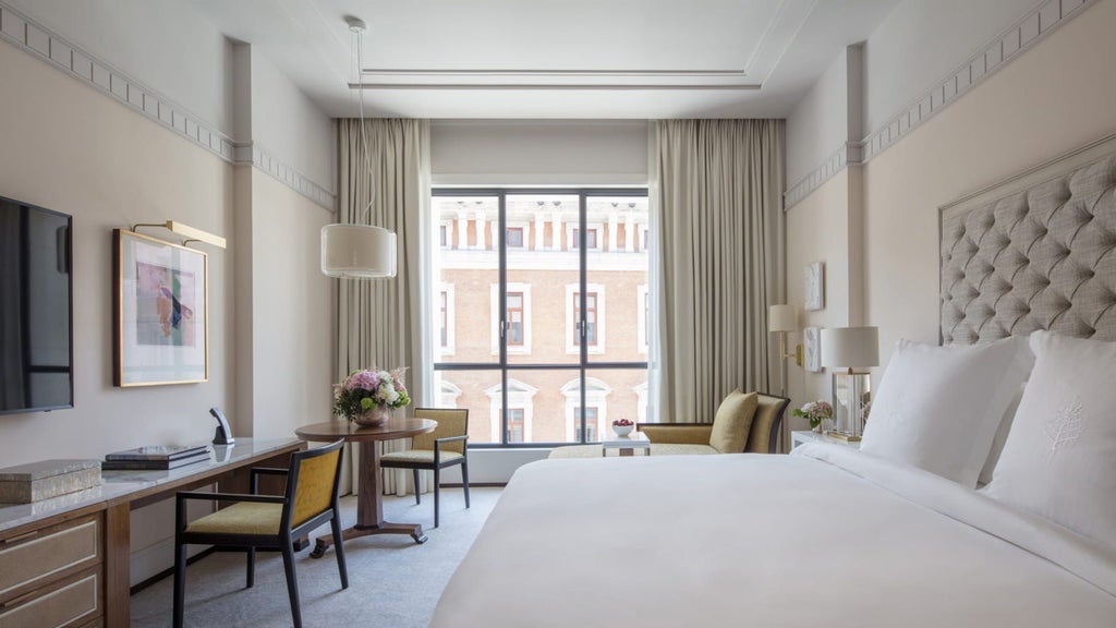 Hotel Suite in Four Seasons Madrid with cream walls, king bed, luxurious seating area, sunlit windows and elegant modern-traditional decor