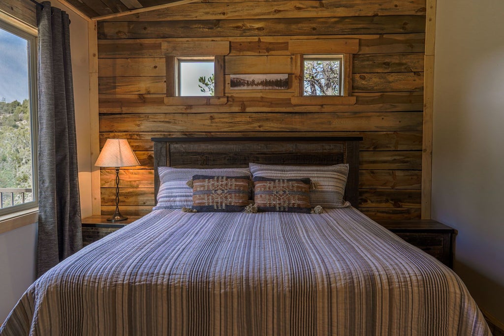 Rustic luxury lodge room with wooden furnishings, plush bedding, and expansive mountain views showcasing natural textures and warm, inviting ambiance near Zion National Park