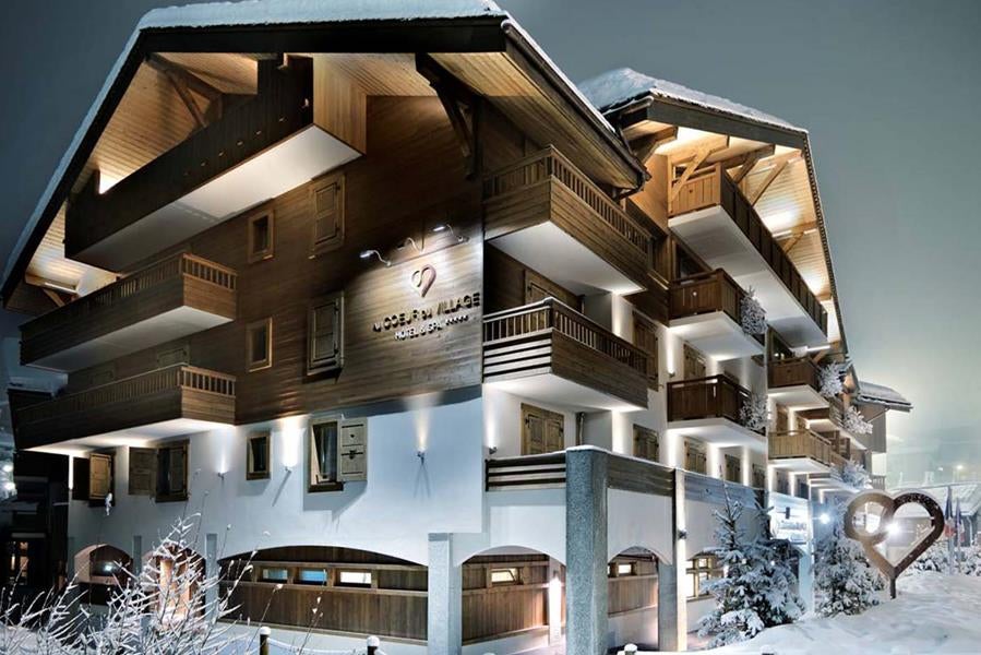 Elegant five-star mountain resort with stone and wood facade, featuring traditional Alpine architecture and upscale spa facilities