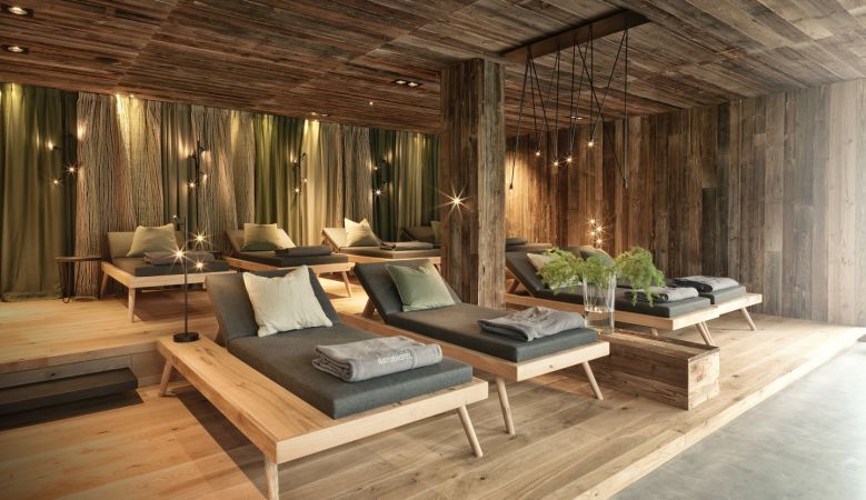 Modern alpine hotel nestled in snowy Austrian mountains, featuring glass-walled spa deck with heated infinity pool and panoramic views