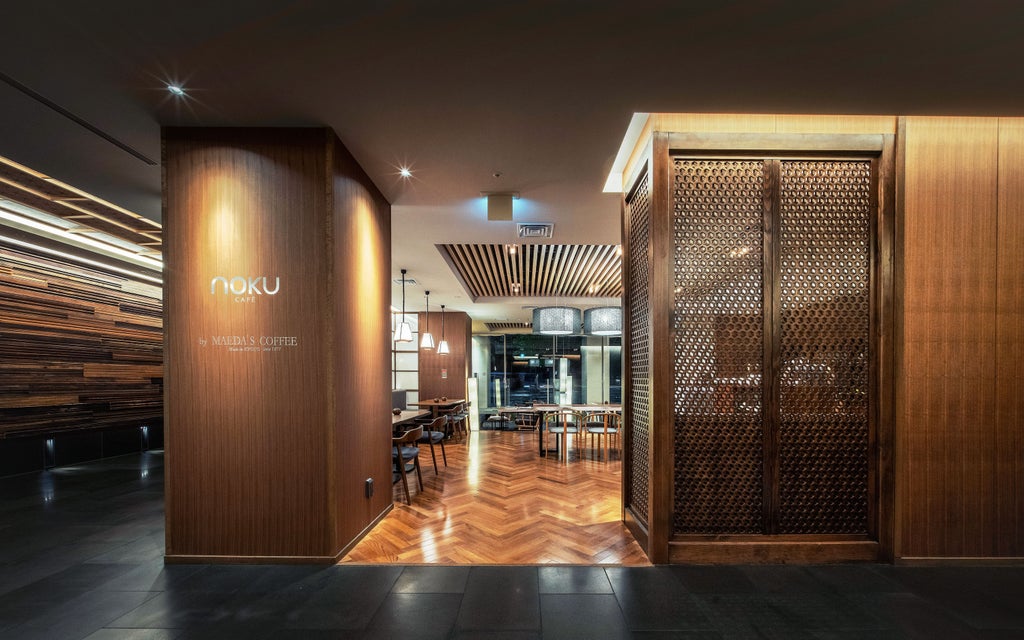 Contemporary Japanese hotel facade at night with warm lighting illuminating traditional wood-slat screens and elegant stone entrance