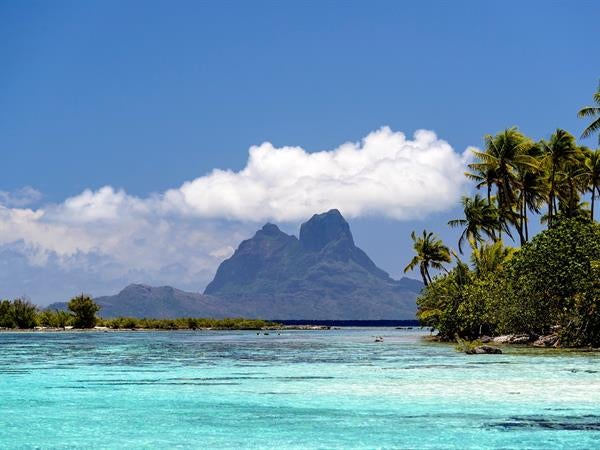 Luxurious overwater bungalow suite with wooden deck, plunge pool, and panoramic views of turquoise lagoon and Mount Otemanu in Bora Bora