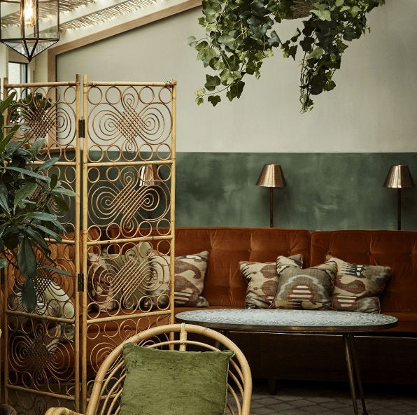 Elegant boutique hotel entrance with green awnings, brass fixtures, and potted plants framing a classic Copenhagen facade at dusk