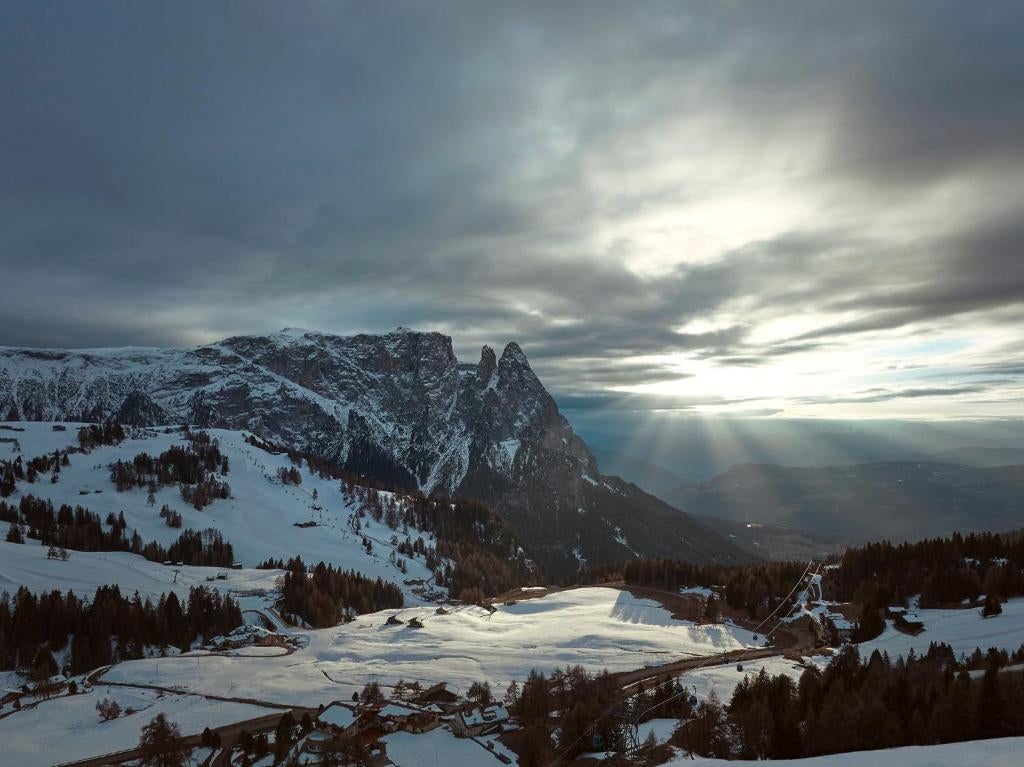 Sleek mountain lodge with glass walls nestled in snowy Dolomites, featuring modern architecture, panoramic terraces and luxury spa wing