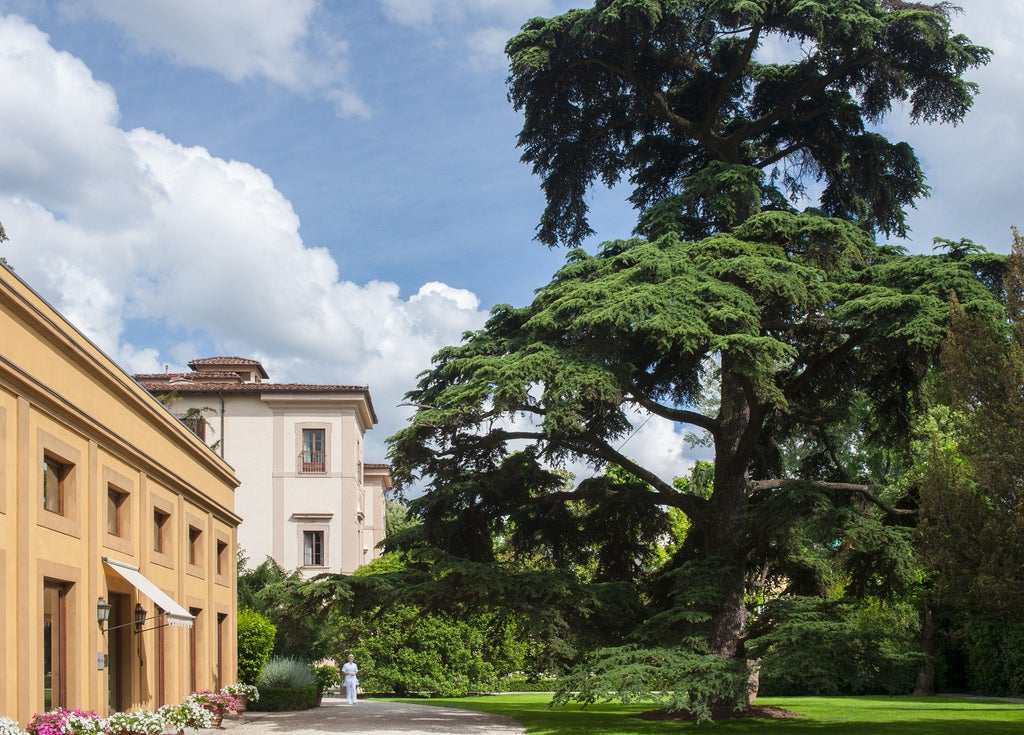 Historic Italian villa turned luxury hotel with manicured Renaissance gardens, ornate fountains and classical architecture at sunset