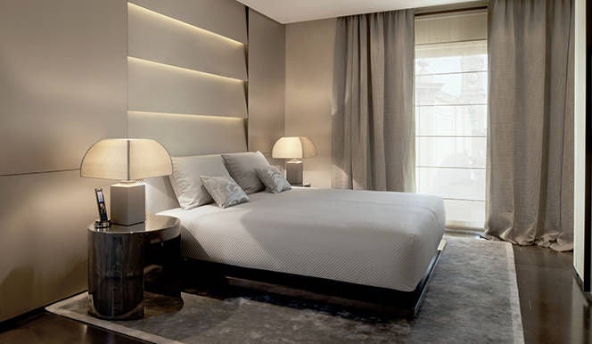 Elegant hotel room with Armani furniture, featuring modern living space, bedroom and limestone bathroom with luxurious amenit