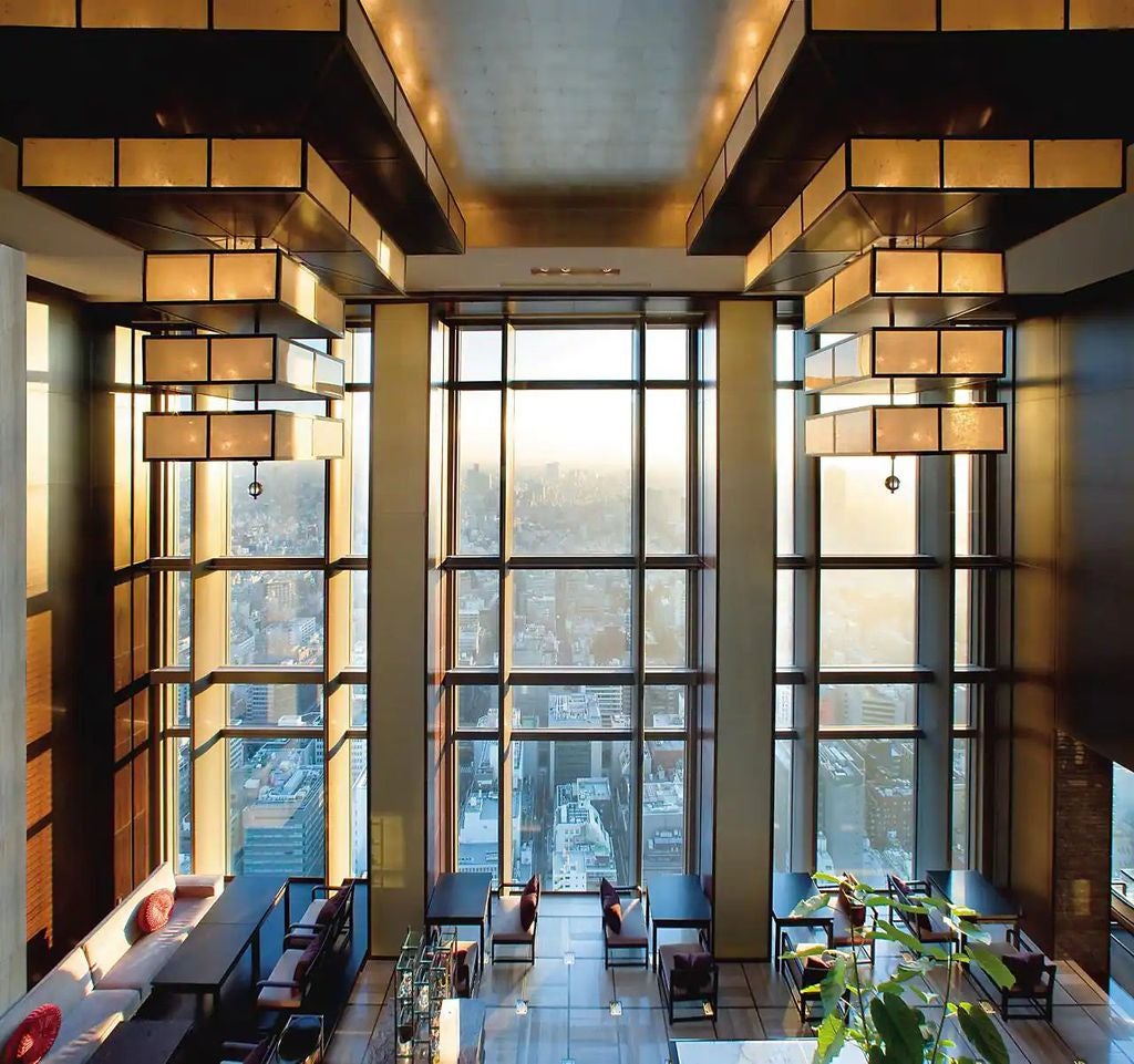 Five-star Mandarin Oriental Tokyo exterior at night, illuminated glass tower soaring above Nihonbashi district with city lights below