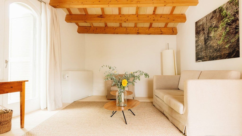 Rustic white stone cottage with private garden, traditional Spanish architecture, nestled among olive trees in a serene Menorcan landscape.