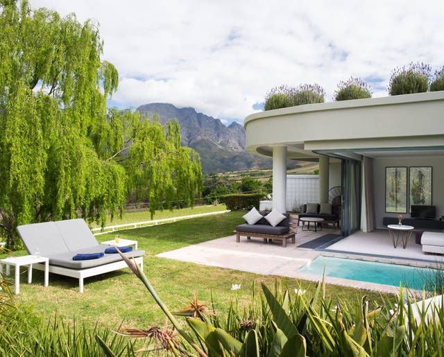 Luxurious vineyard estate with elegant stone buildings, mountain backdrop, and manicured gardens at Mont Rochelle hotel in South African wine country