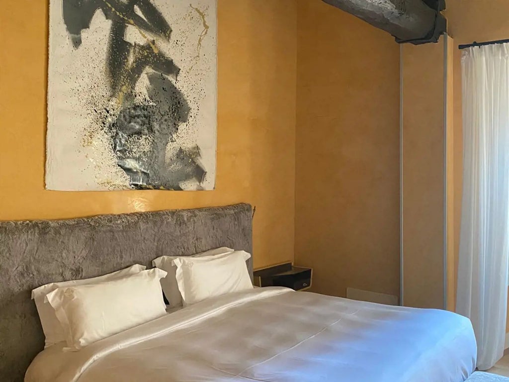 Elegant grand deluxe hotel room with contemporary Italian design, luxurious furnishings, and soft neutral tones overlooking urban Milan streetscape