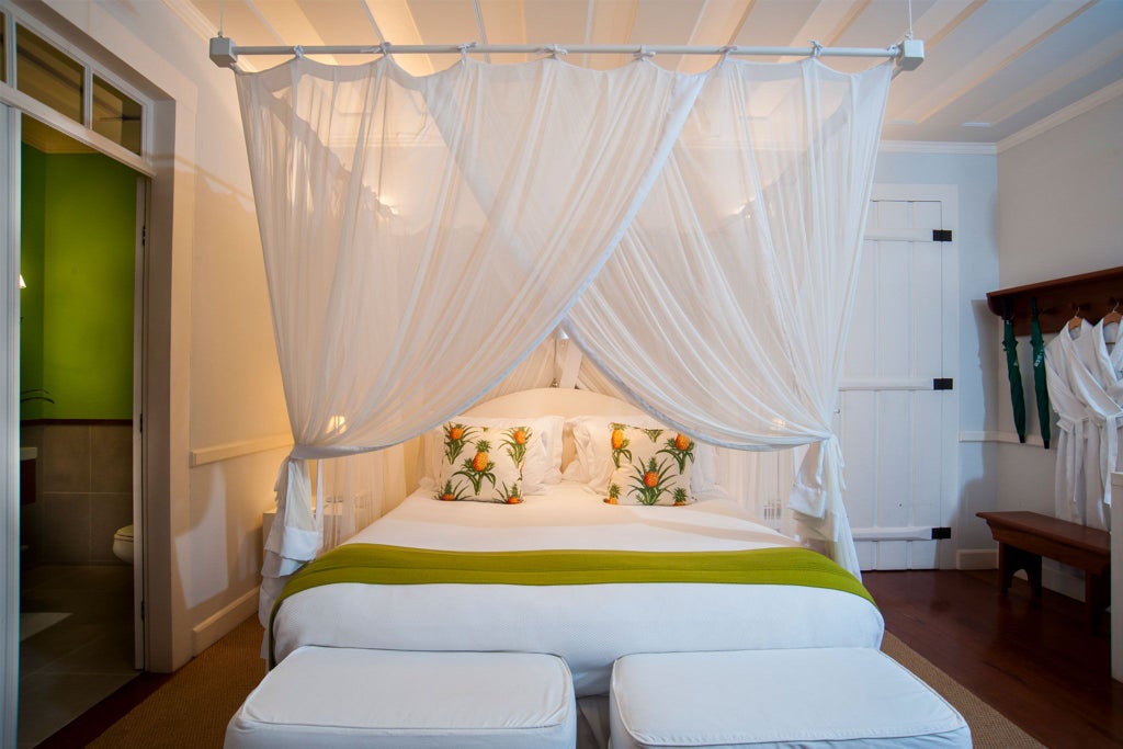 Elegant green-themed luxury suite at Casa Turquesa, featuring plush white bedding, verdant tropical accents, and sophisticated Brazilian coastal design elements