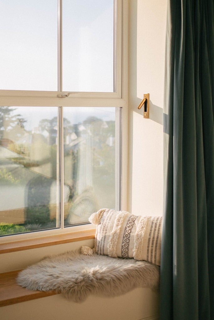 Elegant coastal-inspired hotel room with plush white bedding, nautical blue accents, panoramic sea view, and modern minimalist design at coastal retreat