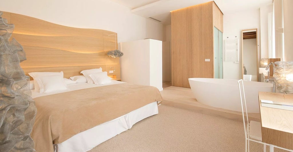 Elegant junior suite in historic Convent de la Missió, featuring minimalist design, stone walls, plush white bedding, and soft lighting in Palma de Mallorca