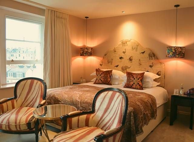 Cozy double hotel room with elegant bird-themed decor, soft neutral tones, plush bedding, modern minimalist furnishings in a UK boutique setting