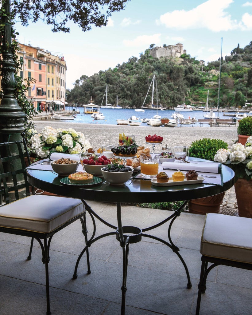 Italian coastal luxury hotel overlooking Mediterranean Sea with infinity pool, white balconies, and cascading terraces amid cliffside gardens