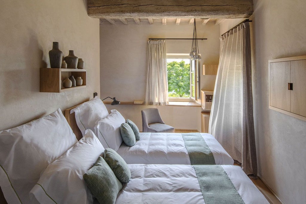 Elegant junior suite at Badia di Pomaio, featuring rustic wooden furnishings, soft neutral linens, and panoramic Tuscan countryside views through large windows