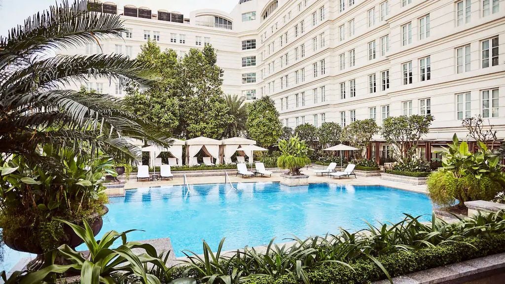 Elegant Park Hyatt Saigon facade with French colonial architecture, palm trees and luxurious entrance with polished marble steps at dusk