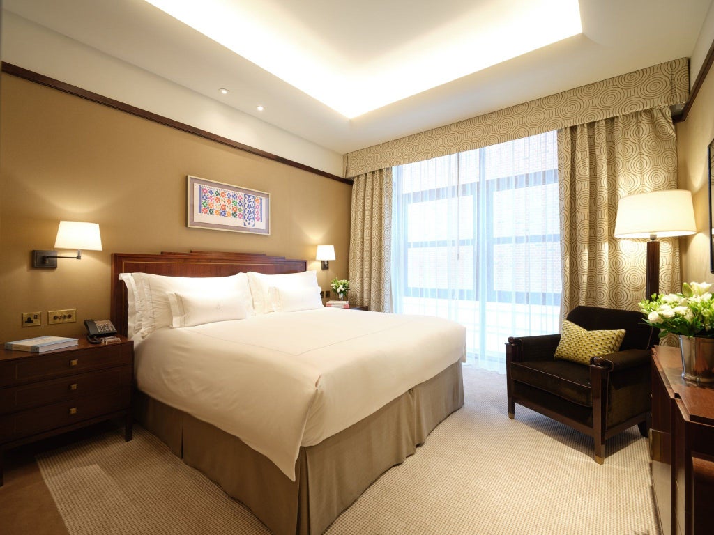 Elegant classic suite with sumptuous king bed, plush cream furnishings, soft lighting, and luxurious marble-tiled bathroom in prestigious Mayfair hotel room