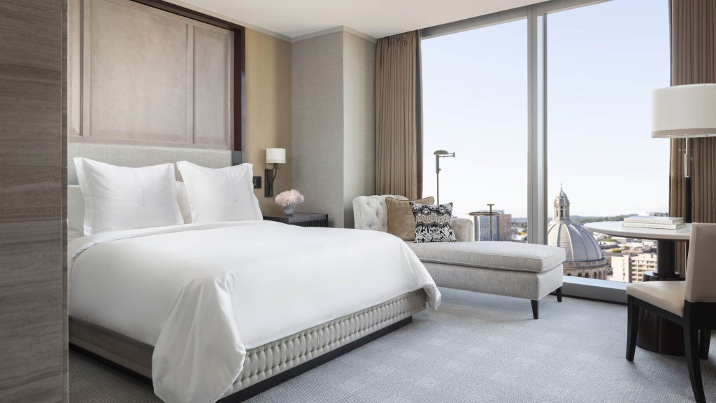 Luxurious Four Seasons deluxe room with expansive city skyline view, featuring modern elegant furnishings and floor-to-ceiling windows in Boston, MA