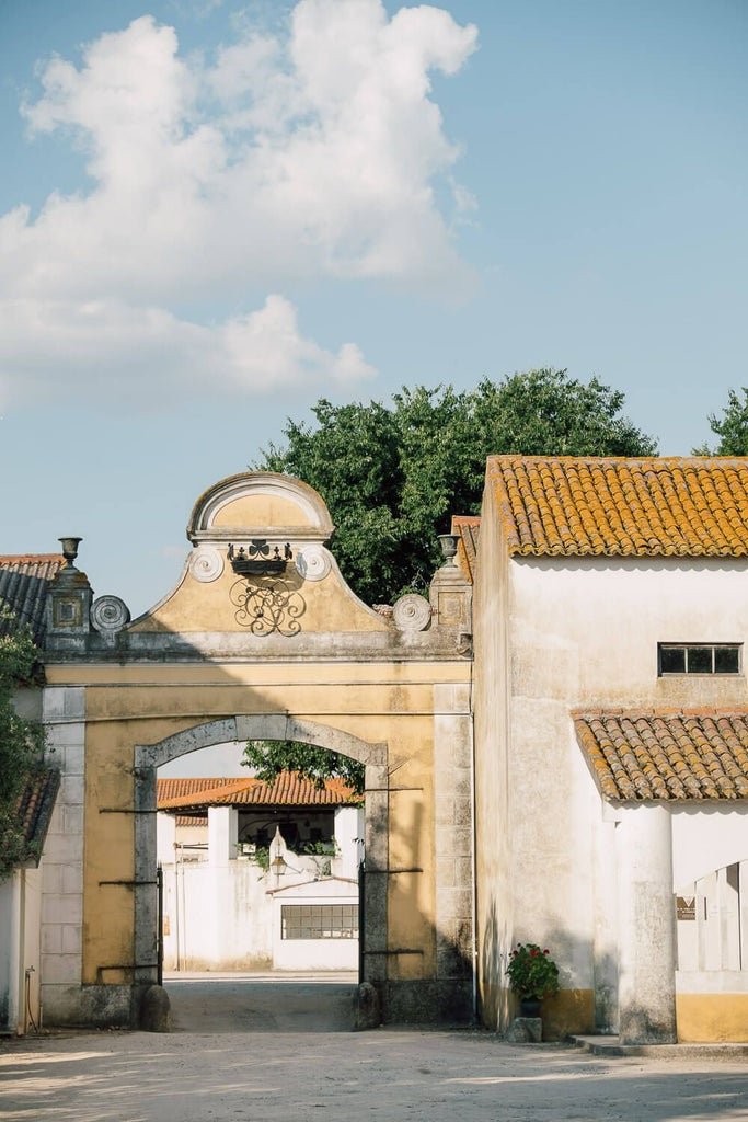 Rustic stone country house with terracotta roof nestled in lush Portuguese countryside, featuring elegant spa buildings and manicured gardens at sunset