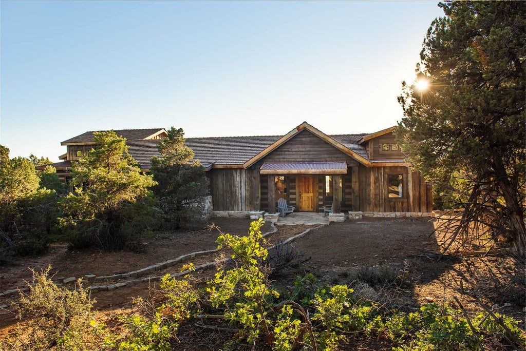 Rustic wooden lodge interior with plush king bed, panoramic mountain views, warm earth tones, and cozy cabin-style furnishings at scenic mountain retreat