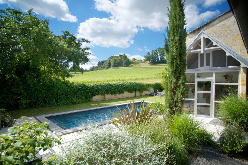 Elegant stone-walled French countryside hotel with verdant gardens, classic architectural details, and warm golden sunlight casting a luxurious ambiance