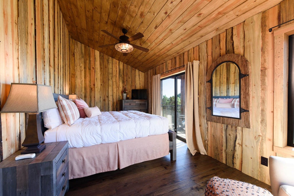 Rustic lodge room with wooden furniture, plush bedding, and scenic mountain view, blending modern comfort with natural wilderness aesthetic at scenic ranch accommodation