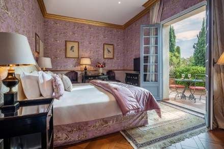 Elegant Provence-style junior suite with soft blue walls, ornate antique furnishings, plush white bedding, and delicate floral accents at Villa Gallici