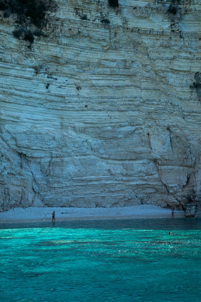 Luxury yacht cruising azure Ionian waters between Paxos and Antipaxos, green islands backdrop, sunlight glimmering on pristine turquoise sea