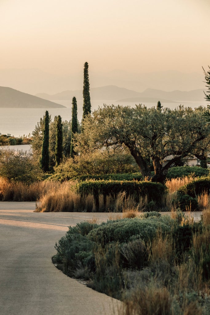 Elegant infinity pool overlooking Aegean Sea at sunset, with white Grecian columns and private villa terraces on a hilltop in Porto Heli