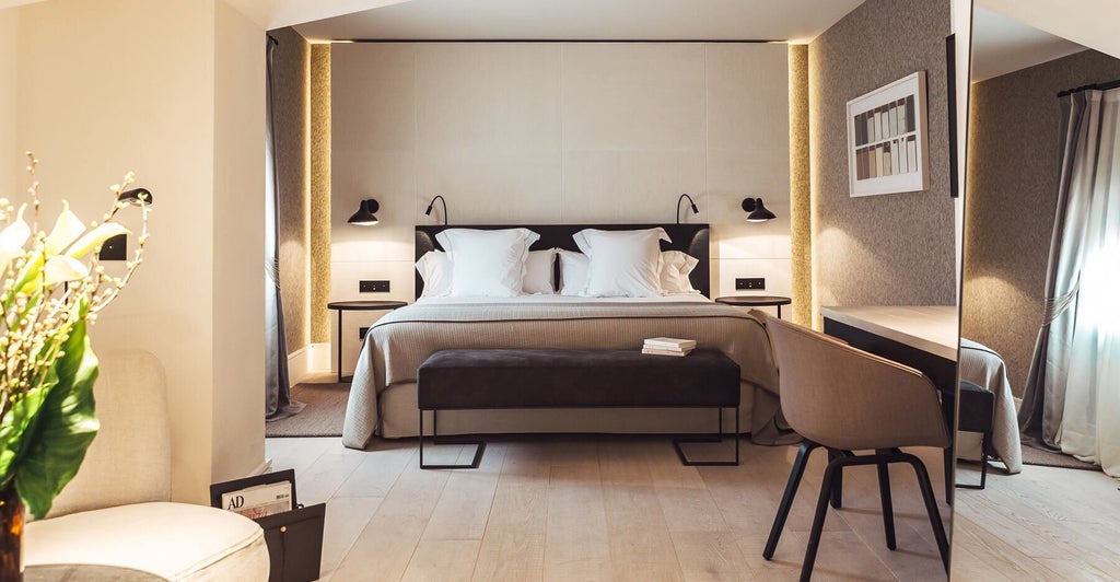 Elegant junior suite with modern minimalist design, featuring neutral color palette, sleek furniture, and large windows overlooking historic Spanish architecture