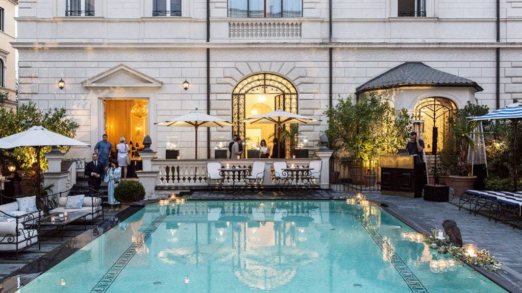 Elegant marble lobby of luxury Hotel Palazzo Dama in Rome, with opulent white columns, contemporary furnishings, and soft dramatic lighting creating a refined atmosphere