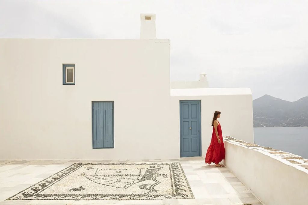 Whitewashed luxury suites with private infinity pools cascade down a hillside overlooking the turquoise Aegean Sea in Milos, Greece